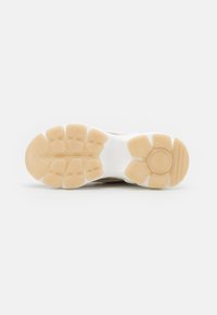 Semelle de chaussure de sport en caoutchouc beige avec un motif de grip texturé. Le design présente une intermédiaire blanche pour le confort et le soutien.