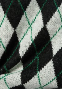 Zwart-wit gestreepte stof met grote diamantvormen, omrand door groene accenten. Zachte textuur, gebreide samenstelling.