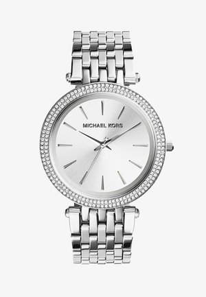 Montre en acier inoxydable argenté avec un cadran rond, une lunette ornée de cristaux et un cadran minimaliste présentant des index et des aiguilles argentés.