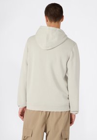 Sudadera ligera gris claro con cordón, que presenta un bolsillo tipo canguro y puños acanalados. El material parece suave y texturizado.