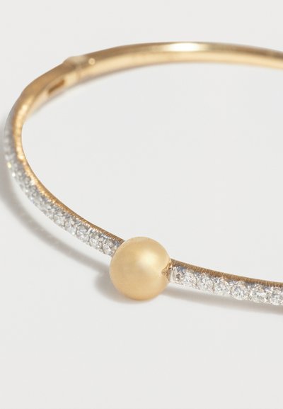 Χρυσό βραχιόλι με σειρές μικρών διαφανών πολύτιμων λίθων και μία μεγάλη ματ χρυσή λεπτομέρεια σε σχήμα χάντρας.
