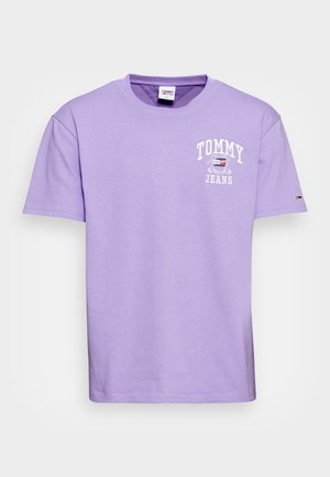 Lavendelfarbenes Tommy Jeans T-Shirt mit kurzen Ärmeln, weißem Logo und kleinem Flaggenemblem auf dem linken Ärmel, auf weißem Hintergrund dargestellt.