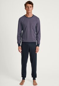 T-shirt à manches longues de couleur marine avec un motif géométrique ; pantalon sombre assorti avec des poignets élastiques. Tissu doux, coupe décontractée et col rond.