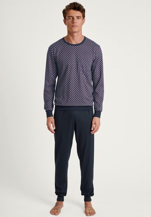 T-shirt à manches longues de couleur marine avec un motif géométrique ; pantalon sombre assorti avec des poignets élastiques. Tissu doux, coupe décontractée et col rond.