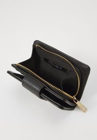 Portefeuille en cuir noir avec fermeture éclair et matériel doré, extérieur texturé, compartiment intérieur avec étiquette de marque visible, fermeture à rabat.