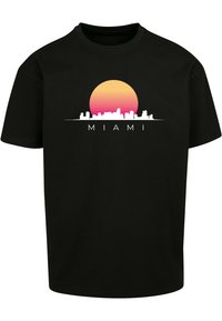 Svart bomull T-skjorte med et grafisk trykk av en solnedgang i gradientnyanser av gult og rosa over en hvit silhuett av Miami skyline.