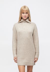 Rochie tricotată bej, cu guler înalt și fermoar până la piept, având mâneci lungi și croială lejeră. Material texturat cu modele ribbed.