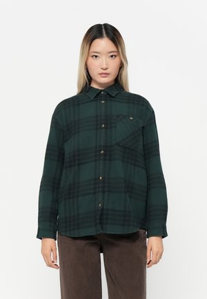 Green plaid flannel shirt with a button-down collar, chest pocket, and gold button accents. Long sleeves, soft texture, and relaxed fit.
