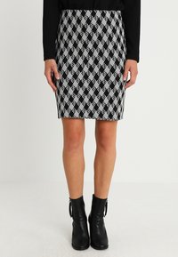 Falda negra y blanca hasta la rodilla con un patrón de diamantes, diseño ajustado, tela elástica, combinada con botas negras hasta el tobillo.