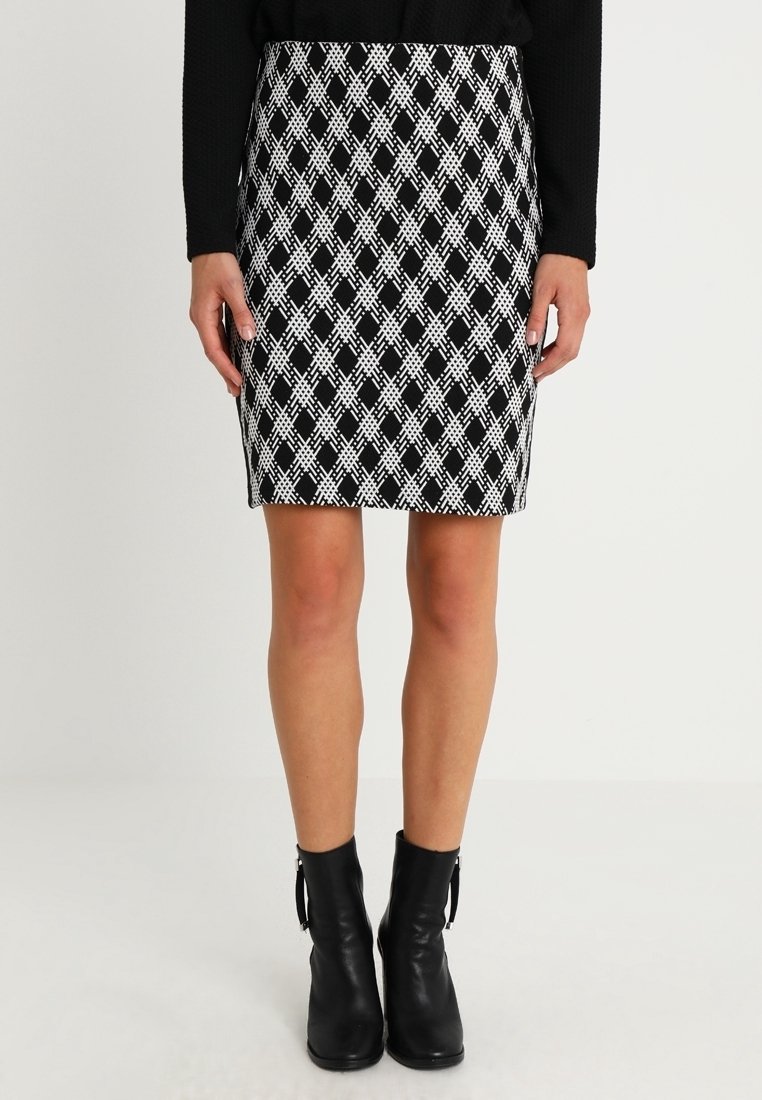 Falda negra y blanca hasta la rodilla con un patrón de diamantes, diseño ajustado, tela elástica, combinada con botas negras hasta el tobillo.