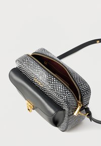 Μικρό τσαντάκι ώμου από μαύρο δέρμα με υφή και λευκή και γκρι φλοράλ πτυσσόμενη πλευρά. Διαθέτει χρυσά μεταλλικά στοιχεία και διπλές θήκες με φερμουάρ.