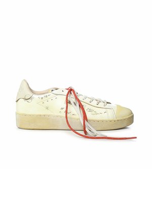 Sneaker crema a taglio basso con lacci rossi e bianchi, scarabocchi disegnati a mano e suola in gomma leggermente consumata su sfondo bianco.