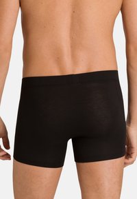 Black boxer shorts with a smooth, elastic waistband. Fitted design with a soft texture. The fabric appears lightweight and breathable.