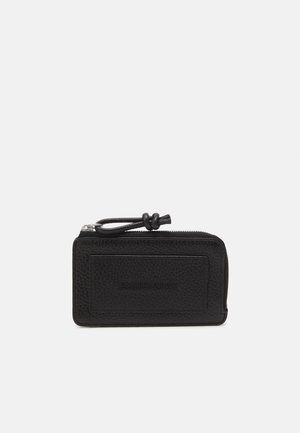 Portafoglio in pelle nera con superficie testurizzata, chiusura a zip e tirante in pelle annodato. Presenta un logo "EMPORIO ARMANI" impresso sul fronte.