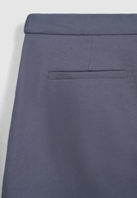 Pantaloni blu navy con finitura testurizzata; presentano una tasca posteriore singola e una vita sartoriale.