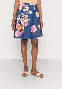 Blommig kjol i marin med rosa och orange blommor, utsvängd design, knälång, tillverkad av lättviktig tyg. Matchas med beige glidsandaletter.