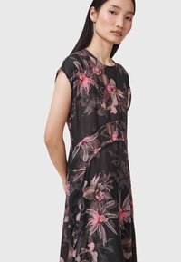 Abito nero a fiori con maniche corte, caratterizzato da motivi florali in rosa e beige, tessuto leggero e silhouette rilassata.