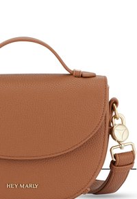 Sac bandoulière en cuir brun texturé avec un rabat arrondi, une poignée supérieure et des ferrures en métal doré. Doté d'une sangle réglable ton sur ton.