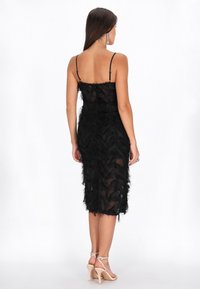 Rochie midi cu pene negre, cu bretele subțiri, din material transparent și cu o siluetă ajustată. Prezintă o textură stratificată și un tiv drept.