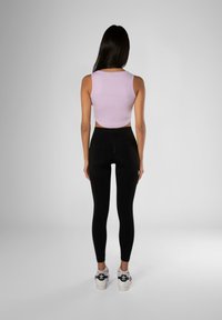 Lila usnjeni crop top, črne legice in bele superge z črnimi detajli. Gladek material, prilegajoča se zasnova in dolžina legic do gležnjev.