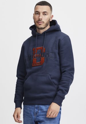 Felpa blu navy realizzata in misto cotone con tasca frontale. Presenta una scritta ricamata "Original" e un grande dettaglio "0" in tonalità arancioni.