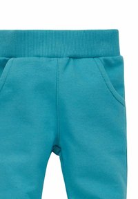 Türkise Jogginghosen mit einem gerippten Bund, elastischem Material und zwei Seitentaschen. Der glatte Stoff sorgt für Komfort und eine einfache Handhabung.