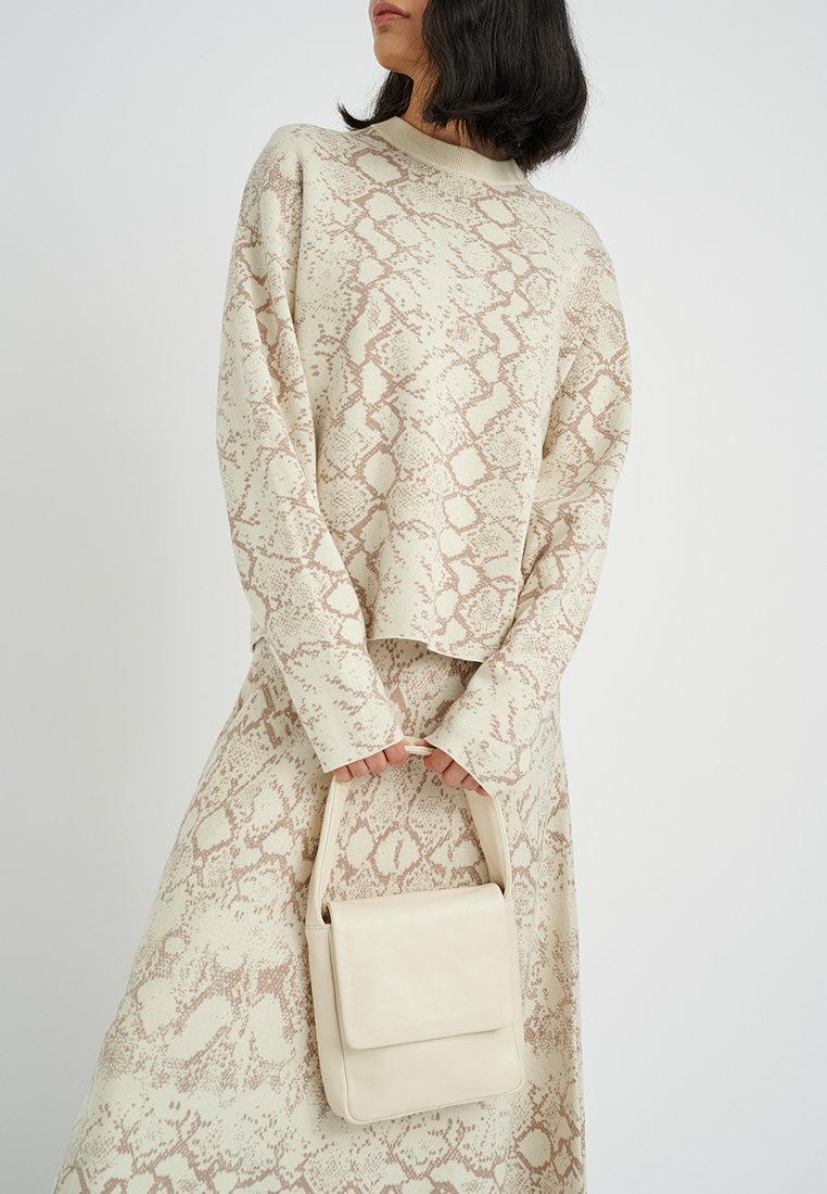 Beige Pullover und Rock im Schlangenhautmuster, mit einer kleinen beige Lederhandtasche in strukturiertem Design und mit Griff.