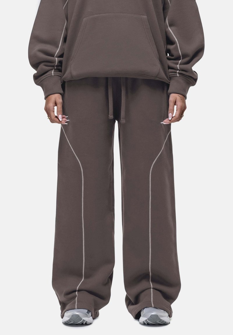 Donkerbruine oversized hoodie met een voorzak en bijpassende wijde sweatpants. Kenmerkt zich door contrasterende witte stiksels en een elastische tailleband.