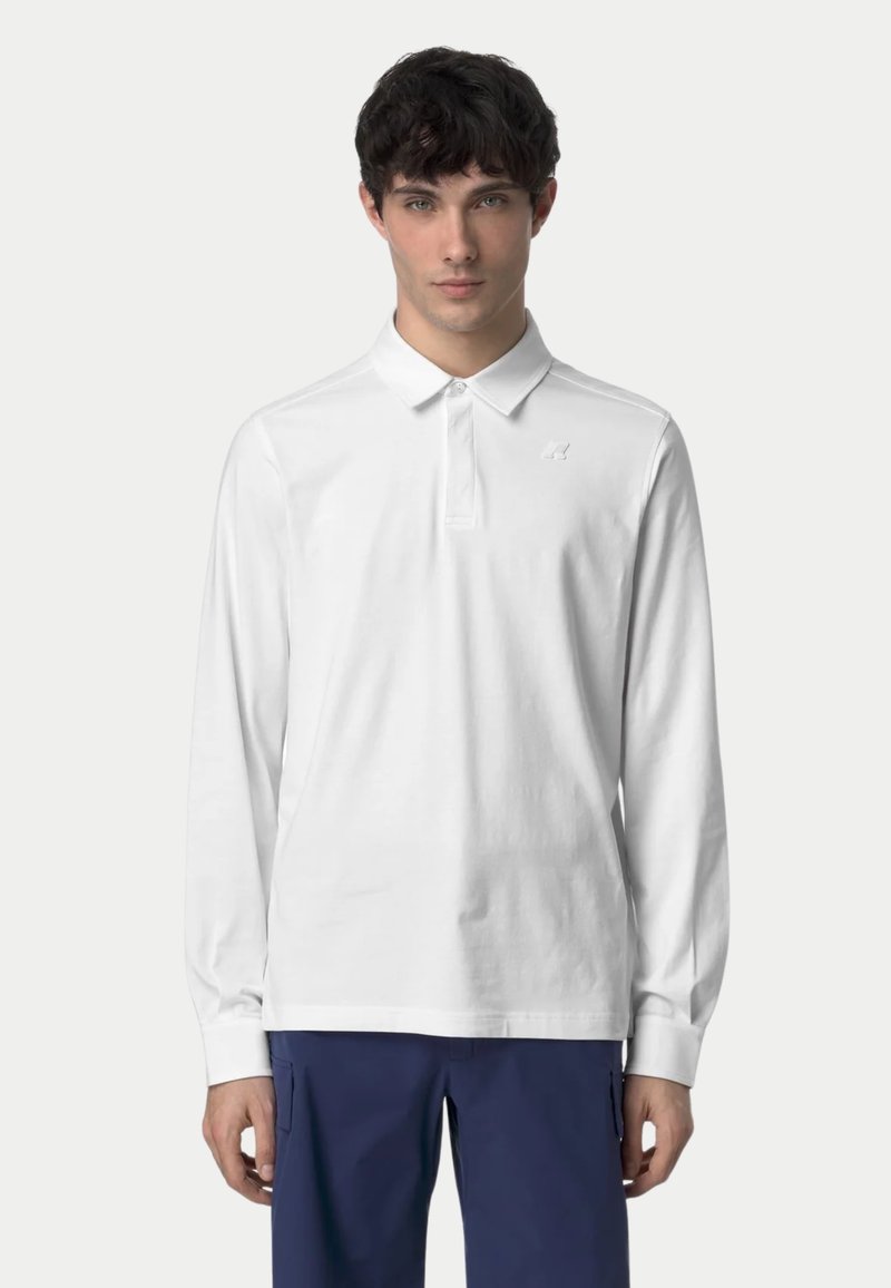 Polo shirt bianco a maniche lunghe con colletto, patta con bottoni e piccolo logo sul petto. Tessuto morbido e fit rilassato.