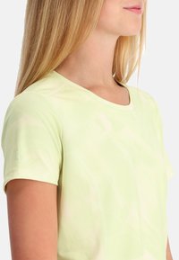 Light green short-sleeve athletic top in a soft, breathable fabric, featuring a rounded neckline and subtle brushstroke pattern.