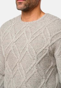 Pull en maille gris clair avec un motif en losanges texturé, col rond et coupe décontractée, fabriqué à partir d'un fil épais et doux.