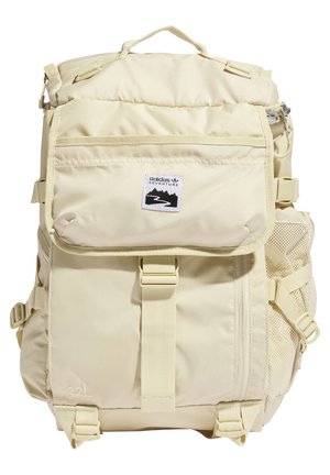 Sac à dos beige Adidas Adventure avec rabat avant, fermeture à boucle, poche latérale en mesh et capacité indiquée de 32 litres.