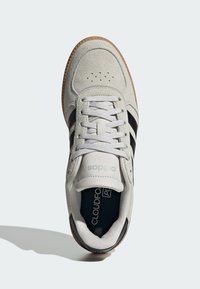 Svjetlosivi tenis s crnim prugama, materijali od brušene kože i kože, bijele vezice, perforirani vrh i gumenim potplatom. Sadrži oznaku "Cloudfoam".