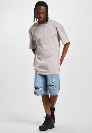 Gray oversized t-shirt with graphic on chest, paired with light blue distressed denim shorts and black combat boots.