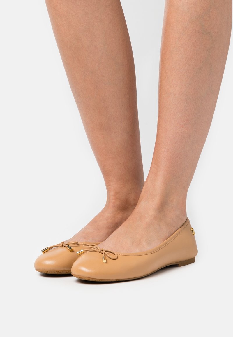 Ballerine in pelle beige con punta rotonda, dettagli decorativi a forma di fiocco e piccoli accenti dorati. Texture liscia, suola piatta.