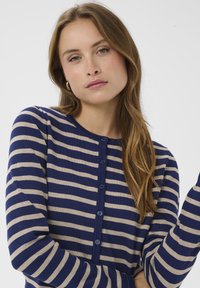 Marineblaue und beige gestreifte Strickjacke mit rundem Ausschnitt, vorne mit Knopfleiste und langen Ärmeln; gestricktes Material mit weicher Textur.