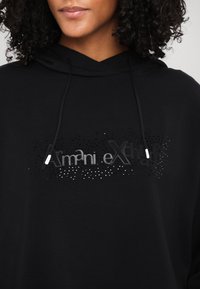 Black hoodie featuring a silver-toned printed logo with stud accents. Soft fabric, adjustable drawstring hood, and relaxed fit design.