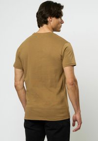 Tricou cu mânecă scurtă, ajustat, din bumbac de culoare maro deschis, cu decolteu rotund. Textură netedă și un design curat, simplu.