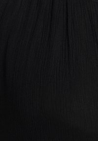 Tela negra con textura arrugada con líneas verticales, acabado suave y ligero brillo, adecuada para diversos diseños de prendas.