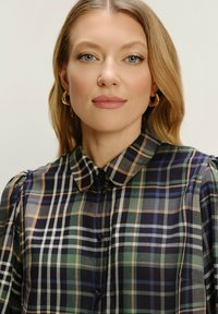 Karirana košulja s dugim rukavima u tamnoplavoj, zelenoj i bež boji, sa strukturiranim ovratnikom i napućenim rukavima, sa usklađenim gumbima i glatkom teksturom.