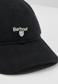 Boné de beisebol preto em algodão com logótipo "Barbour" bordado e design de escudo. Detalhes costurados ao longo da viseira.