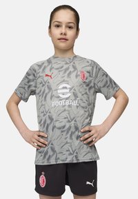 Pilkas kamufliažo rašto futbolo marškinėliai su raudonais akcentais ir logotipu, derinami su juodomis šortais, turinčiais baltą logotipą. Lygus paviršius ir trumpomis rankovėmis.