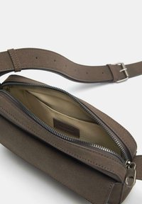Borsa in suede marrone con chiusura a zip e fodera interna morbida. Presenta una tracolla larga con fori regolabili per una vestibilità sicura.