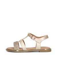 Sandal beige con una fascia frontale glitterata, accenti metallici, design con ritagli e una fibbia regolabile alla caviglia. Suola piatta, texture liscia.