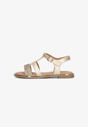 Sandal beige con una fascia frontale glitterata, accenti metallici, design con ritagli e una fibbia regolabile alla caviglia. Suola piatta, texture liscia.