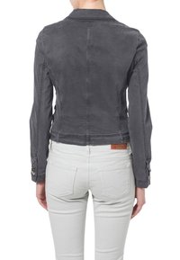 Szara krótka kurtka z miękkiego materiału, z kołnierzykiem, zapięciem na guziki przy mankietach oraz delikatnymi detalami w szyciu. Połączona z jasnymi dżinsami.