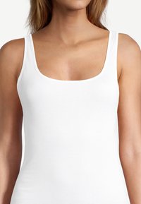 Top bianco senza maniche con scollatura quadrata e spalline larghe. Realizzato in un tessuto liscio e leggero, presenta una silhouette aderente.