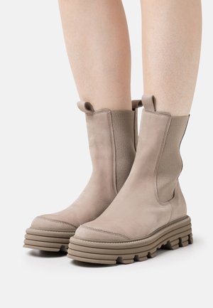 Stivaletti beige in suede con pannelli elastici laterali, suola spessa e testurizzata, e linguette superiori per una facile calzata.