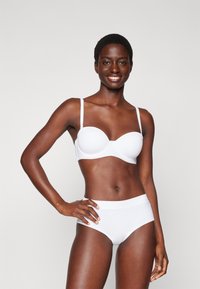 White bra with underwire, smooth fabric, and adjustable thin straps, paired with high-waisted white panties. Both items have a seamless design.