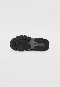 Black rubber sneaker outsole with deep tread patterns, featuring textured surface and a slight gray accent along the midsole.
